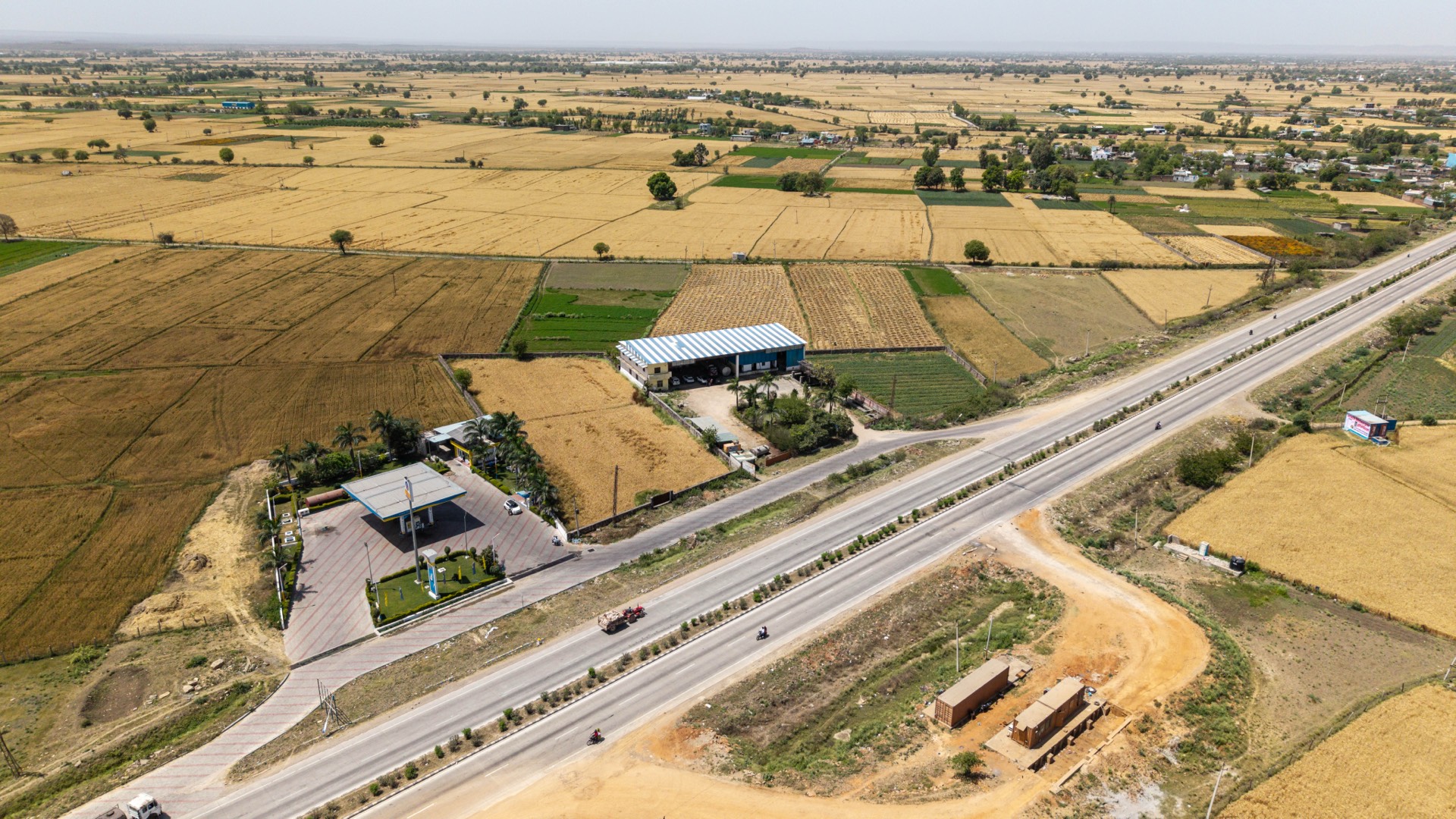 Highway frontage, fuel station, and surrounding farmland from above